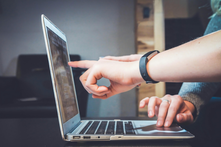 two people pointing at a laptop